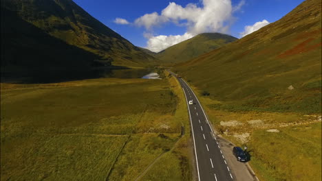 Weißes-Auto,-Das-Auf-Der-Autobahn-In-Den-Schottischen-Highlands-Beschleunigt,-Luftaufnahmen-über-Dem-Kopf