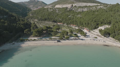 5K-Drone-Tilt-Shot-From-Blue-Sea,-Sandy-Prapratno-Beach-And-Green-Mountainside-In-Croatia-On-Sunny-Day