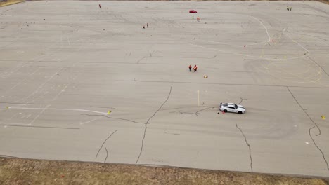 Sport-car-speeding-through-course-on-asphalt,-aerial-drone-view