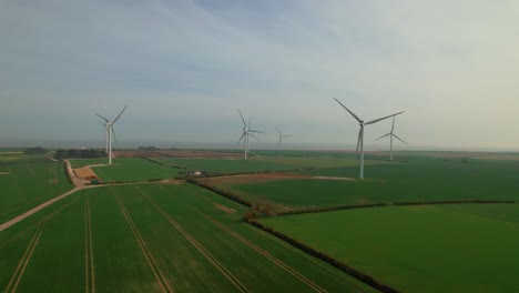 Lissett-airfield-wind-turbine-farm-blades-spin-on-ecological-farmland-meadow-aerial-view-orbit-across-Yorkshire-countryside