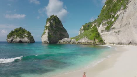 Fit-tourist-woman-in-black-bathing-suit-running-along-turquoise-water-of-Diamond-beach,-Nusa-Penida