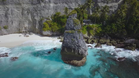 Rock-pinnacle-with-turquoise-blue-water-at-shore-of-Diamond-Beach,-Nusa-Penida,-aerial