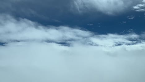 Vista-Aérea-Desde-Una-Cabina-Mientras-Volaba-Entre-Capas-De-Nubes-Blancas-Suaves-Y-Cielo-Azul