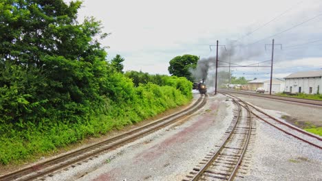 Ein-Erhöhter-Blick-Auf-Einen-Großen-Personenzug-Mit-Dampfmaschine,-Der-An-Einem-Bewölkten-Tag-Rauch-Auf-Einem-Abstellgleis-Vorbeizieht