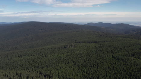 Pan-up,-reveal-lush-beautiful-forest-covered-mountains-near-Prague,-Czech-Republic,-aerial