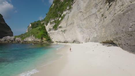Woman-tourist-enjoying-secluded-tropical-white-beach-all-by-herself,-Diamond-Beach-on-Nusa-Penida,-aerial