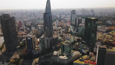 Drone-shot-through-Ho-Chi-Minh-City,-Vietnam-during-sunset-with-the-Bitexco-tower