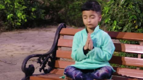 young-kid-meditating-at-wood-bench-in-traditional-dress-at-evening-from-different-angles