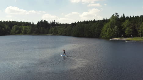 A-lone-young-man-enjoying-smooth-calm-waters-while-out-paddling-a-SUP,-aerial-orbit