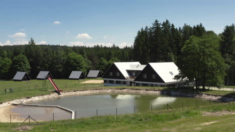 A-luxury-chalet-and-small-cabins-near-a-swimming-pond-at-a-beautiful-resort,-Czech-Republic,-aerial