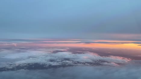 Aerial-view-from-a-cockpit-flying-between-layers-of-clouds-in-the-sunset,-with-an-orange-sky