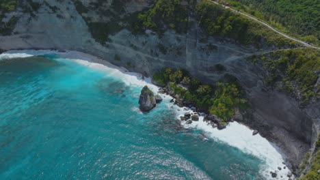 Tourist-attraction-Diamond-Beach-on-tropical-island-Nusa-Penida,-vibrant-blue-water,-aerial