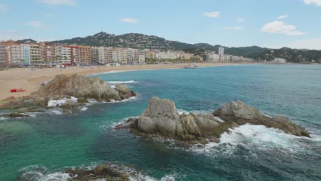 View-of-the-main-beach-of-Lloret-de-Mar-with-the-buildings-in-the-background-and-the-transparent-turquoise-blue-water-of-the-beach-recorded-in-4K-10bit