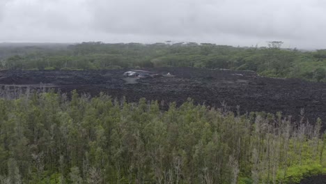 Vista-De-Pájaro-De-Un-Vuelo-Sobre-Lava-Endurecida-De-Una-Erupción-Volcánica-En-La-Isla-De-Hawaii-Con-Una-Casa-En-Medio-De-La-Masa-De-Magma