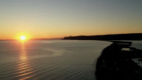 beautiful-timelapse-of-the-sunset-over-the-flat-rippling-ocean-and-the-shores-with-its-beautiful-orange-glow