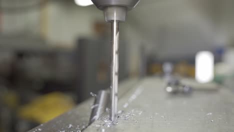 Closeup-Of-A-Drill-Bit-Drilling-Aluminium-In-A-Industrial-Manufacturing-Workshop