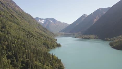 Luftaufnahmen-Eines-Fluges-über-Einen-Riesigen-See-Zwischen-Den-Bergen-Mit-Den-Riesigen-Kiefernwäldern-Auf-Beiden-Seiten-In-Alaska