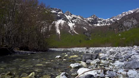 Paradiesische-Alpine-Berglandschaft-Mit-Klarem-Wasser,-Das-Von-Hohen-Schneebedeckten-Gipfeln-In-Albanien-Strömt