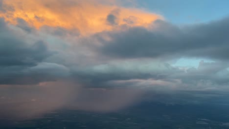 Vista-Aérea-Desde-La-Cabina-De-Un-Jet-Acercándose-Al-Aeropuerto-De-Sevilla-De-Un-Enorme-Cumuloninbus-Mientras-Llueve-Con-Nubes-Naranjas