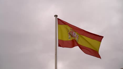 Nahaufnahme-Der-Spanischen-Flagge,-Die-In-Zeitlupe-Gegen-Den-Grauen-Himmel-Weht