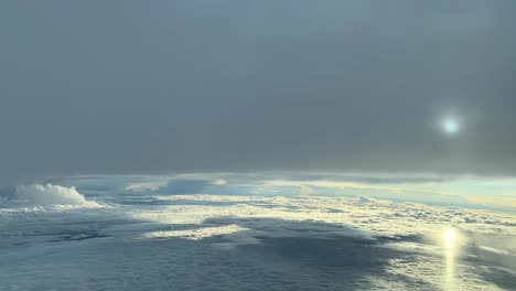 Aerial-view-taken-from-a-jet-cockpit-flying-between-layers-of-cluds-with-a-hidden-sun-and-reflections