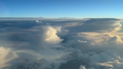 Aerial-view-from-a-jet-cockpit-near-some-huge-cumulonimbus-in-the-sunset-during-the-cruise-level