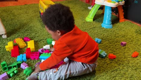 Exotic-two-year-old-african-european-child-playing-at-home-with-color-plastic-blocks-happy-and-funnny