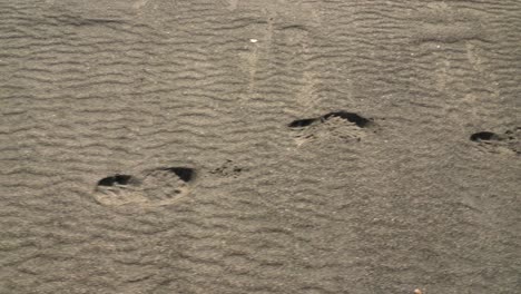 Close-up-panning-shot-of-footprints-on-White-sandy-beach-at-Sandur-on-Sandoy-during-sunny-day
