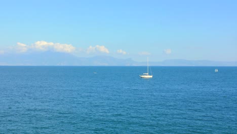 Beautiful-view-of-the-Mediterranean-Sea-with-crystal-clear-blue-water,-mountains-and-sailing-boat-filmed-from-Naples,-Italy