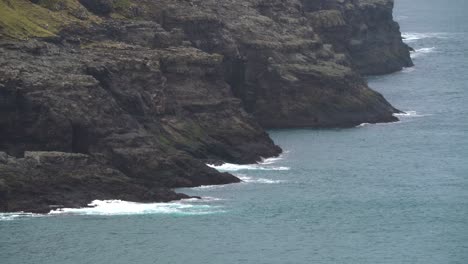 Static-wide-shot-showing-waves-crashing-against-rocky-coastline-of-Faroe-Islands