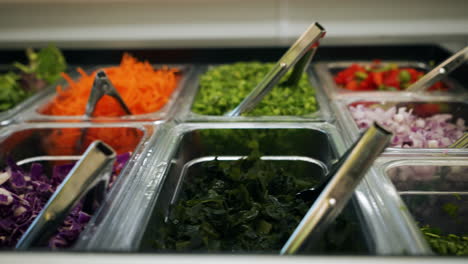 Colorful-salad-bar-options,-shredded-and-prepped-vegetables-fill-bins-on-salad-bar,-slider-4K