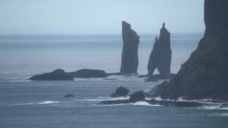 Wide-shot-of-Risin-og-Kellingin-sea-stacks-on-Faroe-Island-with-Atlantic-Ocean-in-background---Slow-motion