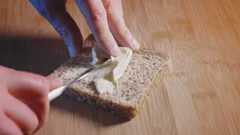 Spreading-Cheese-Triangle-On-A-Slice-Of-Whole-Grain-Toast-With-Spreader-Knife