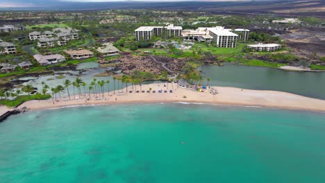 Aerial-pull-back-over-Anaehoomalu-Bay,-Hawaii-beautiful-tropical-beach-with-clear-blue-waters