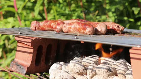 Sausages-sizzling-on-barbecue-over-hot-coals