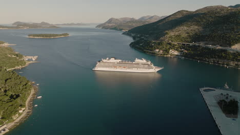 Boat-Cruise-Ship-In-Scenic-Harbor-In-Dubrovnik,-Croatia-In-Afternoon-Sun,-Aerial-5K-Drone