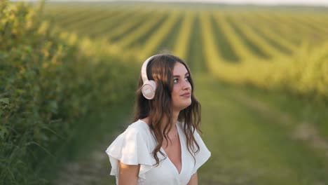 beautiful-young-woman-sitting-in-a-field-listening-to-music-on-headphones