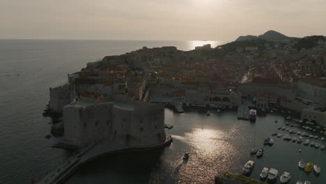 Aerial-5K-Drone-Over-Oceanside-Dubrovnik-Fortress-And-Boat-Marina-In-Bright-Afternoon-Sunlight-In-Croatia