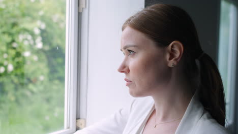 Depressed-and-stressed-woman-looking-out-of-a-window-with-sadness-and-confusion-on-her-face-as-she-is-thinking