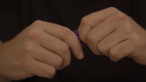 Male-hands-struggling-to-open-purple-condom-package