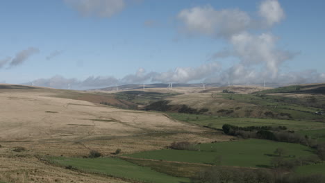 4k-Grüne-Felder-Mit-Windkraftanlagen-Im-Hintergrund-Mit-Dramatischem-Blauem-Himmel