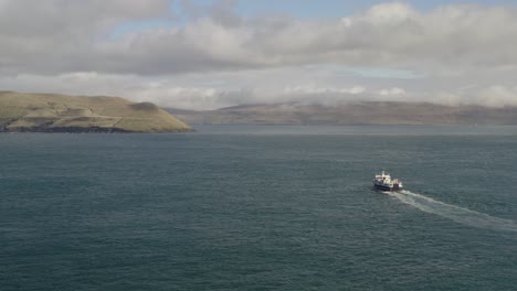 Vista-Aérea-Del-Ferry-Que-Navega-Por-El-Océano-Atlántico-A-La-Isla-Sandoy-Durante-El-Día-Nublado,-Islas-Feroe