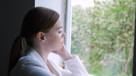 A-Pensive-Woman-Looks-Out-The-Window-Deep-In-Thought
