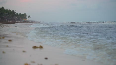 Low-Angle-Shot-Of-Small-Waves-Rolling-And-Breaking-On-Tropical-Beach-Shore-During-Gray-Evening-After-Sunset