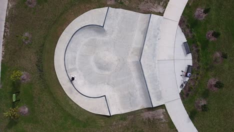 Aerial-drone-shot-of-skateboarder-skating-unique-bowl-in-urban-community-park