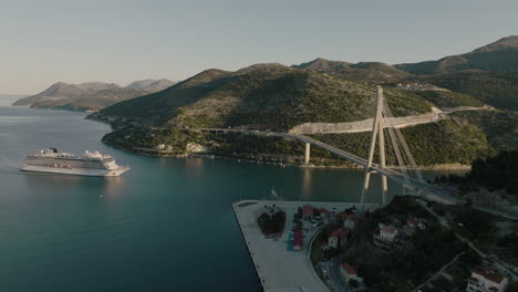 Aerial-5K-Drone-Of-Seaside-Cable-Bridge-And-Cruise-Ship-In-Dubrovnik,-Croatia-Harbor