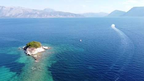 Boat-Sails-to-Reef-and-Small-Island-near-Meganisi,-Lefkada,-Greece---Aerial