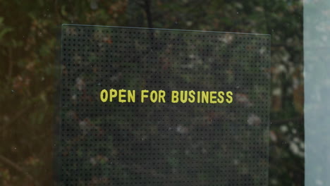 A-businessman-placing-an-open-for-business-sign-in-window