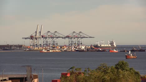 International-harbor-with-cranes-and-containers,-surrounded-by-rusty-old-boats