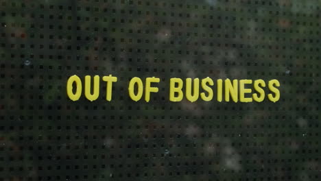 Man-Placing-An-Out-Of-Business-Sign-On-A-Window